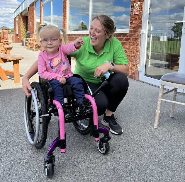 Luna in her awesome pink wheelchair with a Whizz Kidz team member next to her