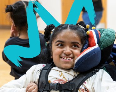 A young wheelchair user smiles facing the camera