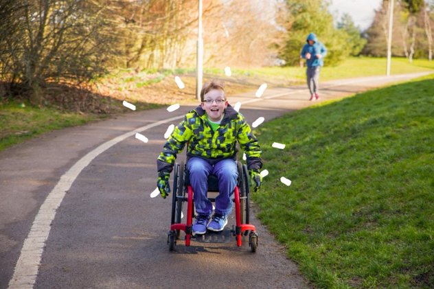 A young wheelchair user pushed himself down a pathway