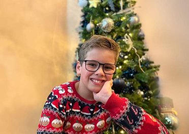 Jacob in a super cool Christmas jumper in front of a Christmas tree