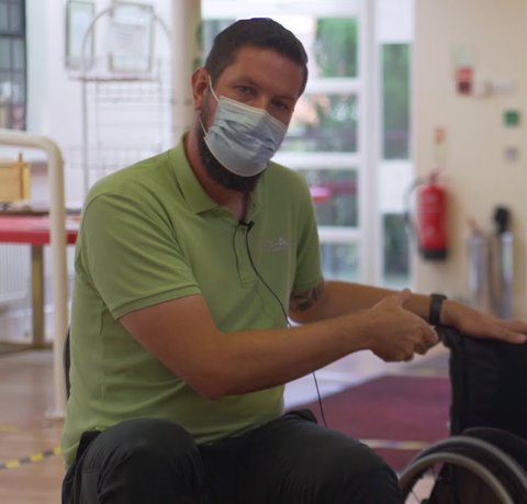 A Whizz Kidz clinician holds a manual wheelchair