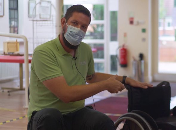 A Whizz Kidz clinician holds a manual wheelchair