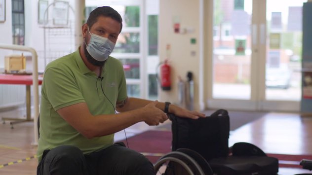 A Whizz Kidz clinician holds a manual wheelchair
