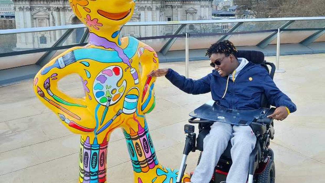 Kashyani sits in their powered chair next to Morph with St Pauls in the background