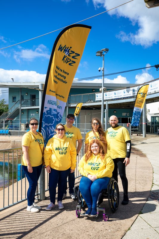 group shot of Whizz Kidz staff at an event including Sophie who is in the front in her wheelchair.