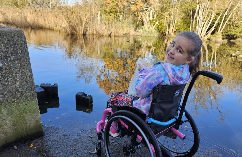 A young wheelchair user sits by a river