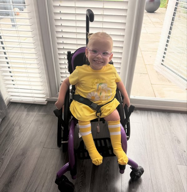 Robyn sits in her wheelchair, smiling cheekily.