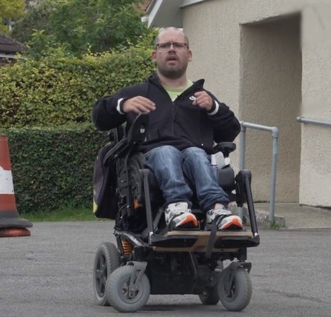 Our wheelchair skills trainer in his powered chair outside a single story building