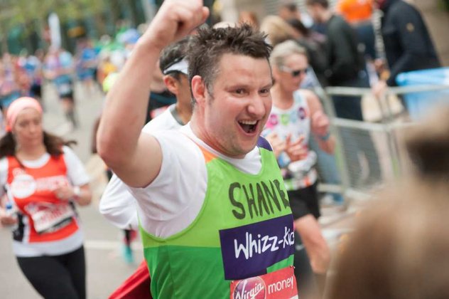 A runner in a green Whizz Kidz top raised his arm as he runs past the camera