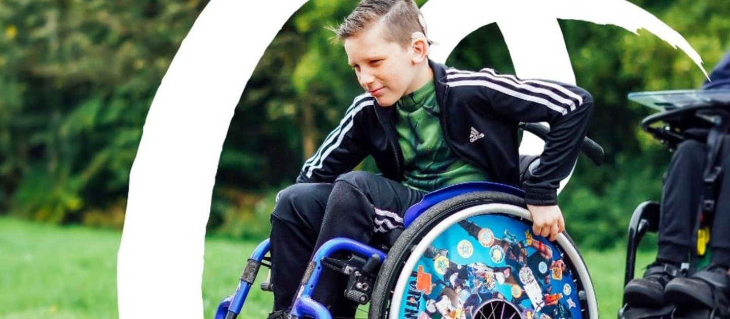 A young wheelchair user rolls on his back wheels