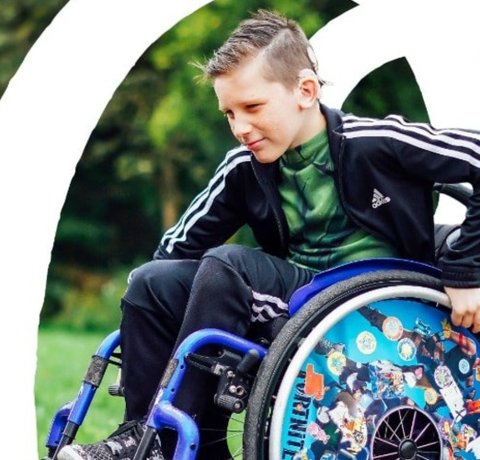 A young wheelchair user rolls on his back wheels