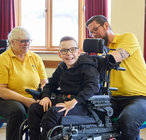 Engineer John Bearman adjusts Logan's wheelchair as he's had another growth spurt, while Sarah looks on