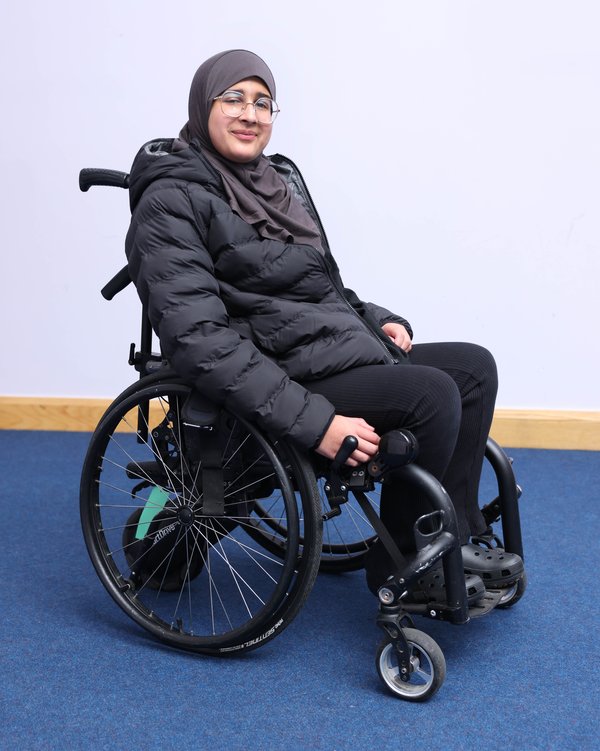 Sophia, a teenage girl who wears glasses and a hijab, sits in her wheelchair