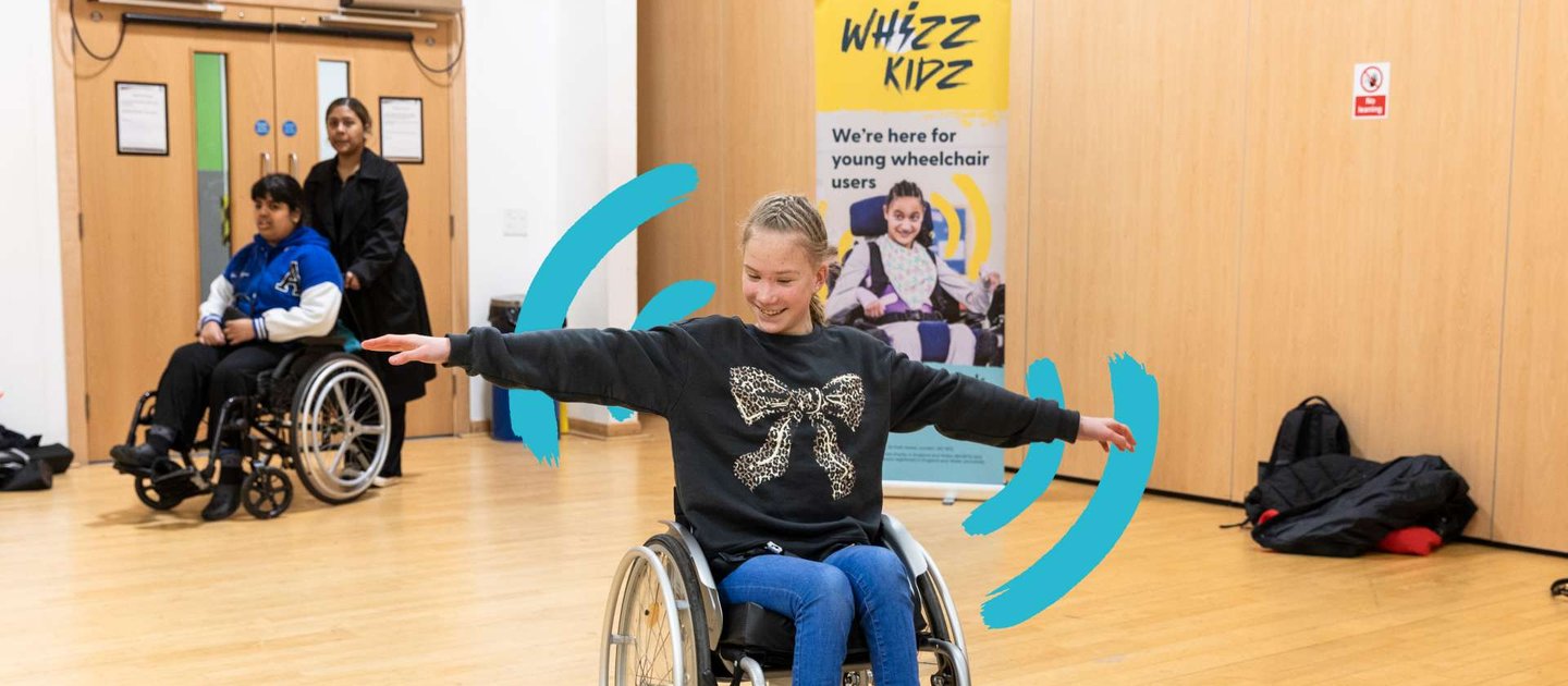 A young wheelchair user has outstretched arms as she participates in one of our skills sessions in a sports hall