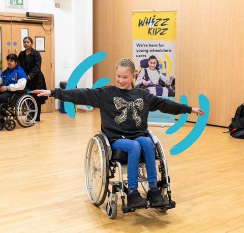 A young wheelchair user has outstretched arms as she participates in one of our skills sessions in a sports hall
