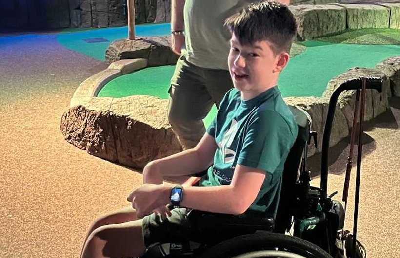 Zach in his black wheelchair on a mini-gold course