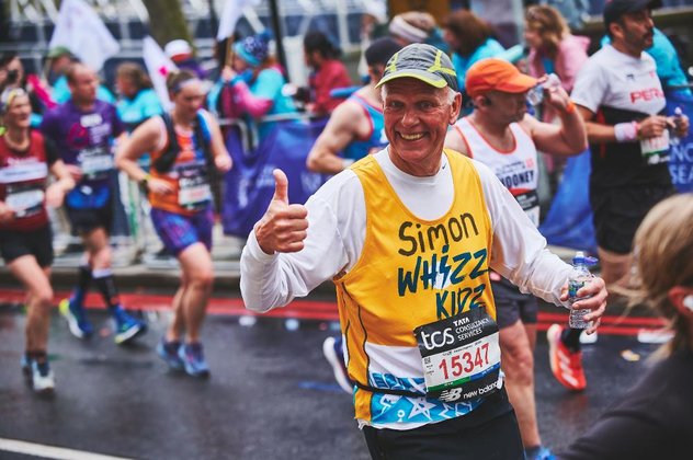 A runner in a yellow Whizz Kidz running vest gives us a thumbs up
