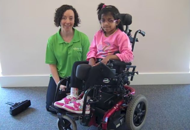 A Whizz Kidz staff member with a young wheelchair user in her super cool powered chair