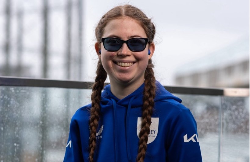 Rebecca portrait. She is looking at the camera smiling, wearing dark glasses and a blue hoody.