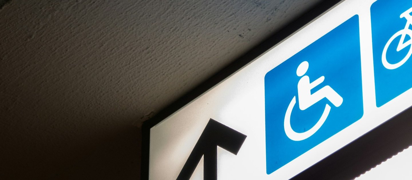 A sign points forward with a wheelchair icon next to it