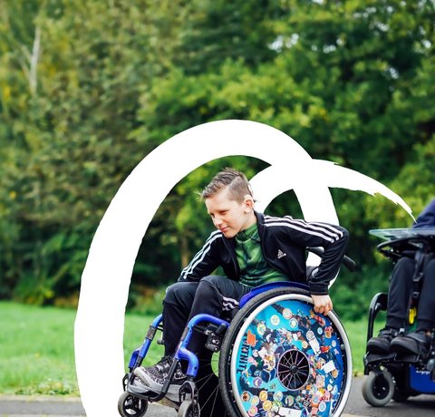 A young wheelchair user rolls on his back wheels
