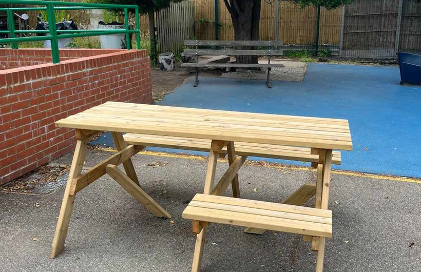 A wooden picnic table with a space for a wheelchair user