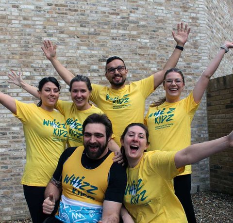 A group all wearing Whizz Kidz t-shirts pose with their arms out