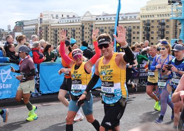 Two runners in yellow Whizz Kidz running vests give us a wave