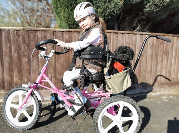 Carmella smiles as she uses her awesome pink trike with her dog, Tinker in the basket