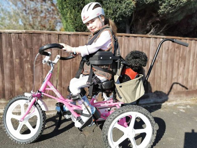 Carmella smiles as she uses her awesome pink trike with her dog, Tinker in the basket