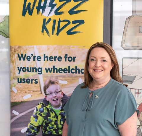 Jo stands next to a Whizz Kidz pull up banner