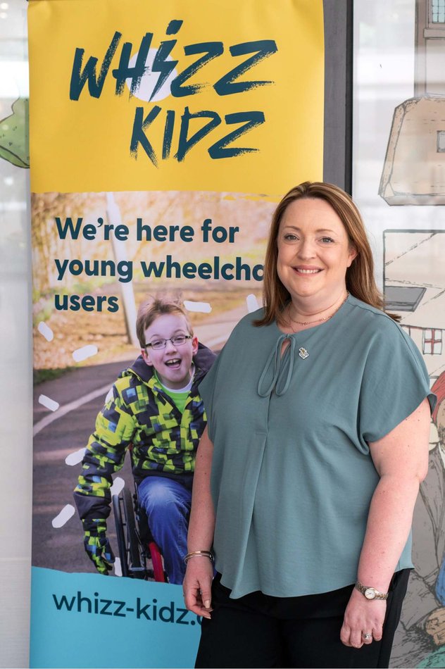 Jo stands next to a Whizz Kidz pull up banner