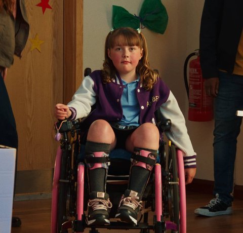 Amber wheels away from her mum at an after school club in her bright pink wheelchair