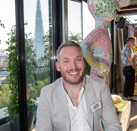 Martin Dougan sits in front of a Morph statue wearing a smart jacket and jeans