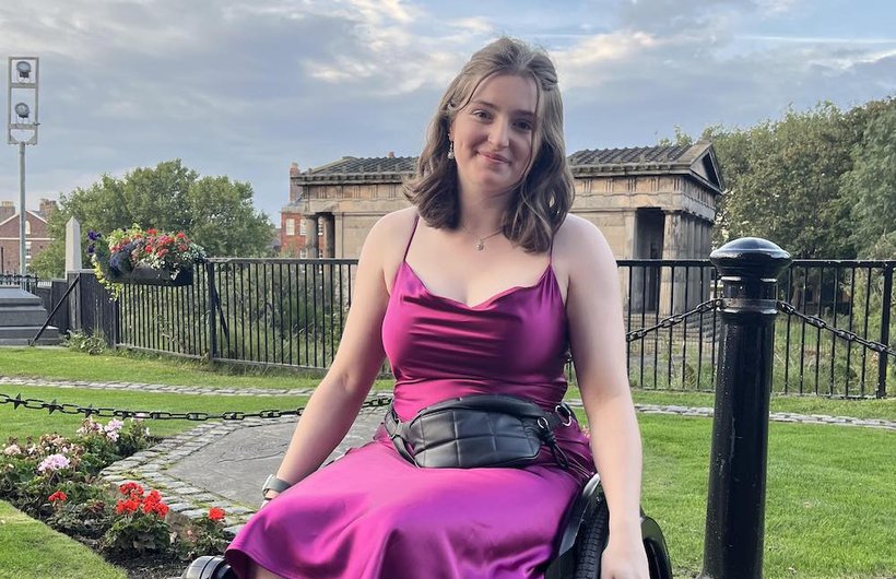 Ella wearing a purple dress in her manual wheelchair