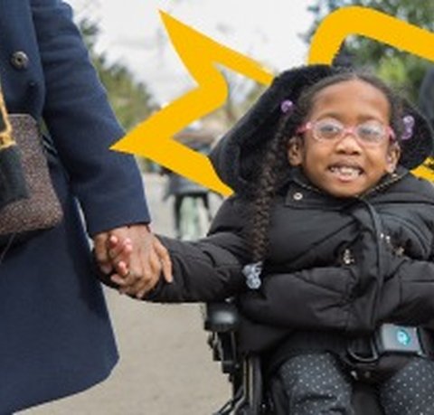 Kiyo-Rei holding her mother's hand as she moves along a pathway in her powered wheelchair