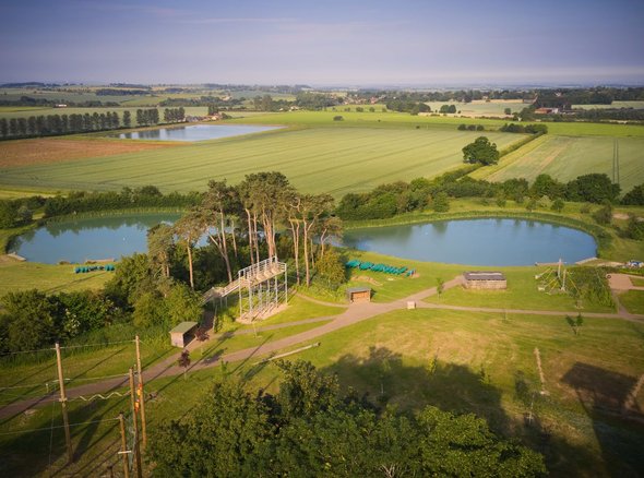 An aerial view of the PGL activity centre showing a beautiful lake, woodlands and fields