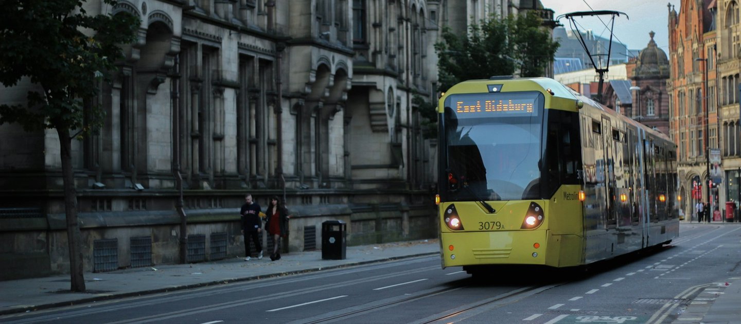 A yellow tram makes its way through the streets on Manchester