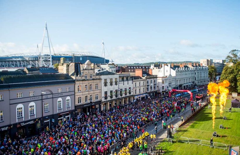 A mass of runners run through Cardiff with the Millennium Stadium in the background