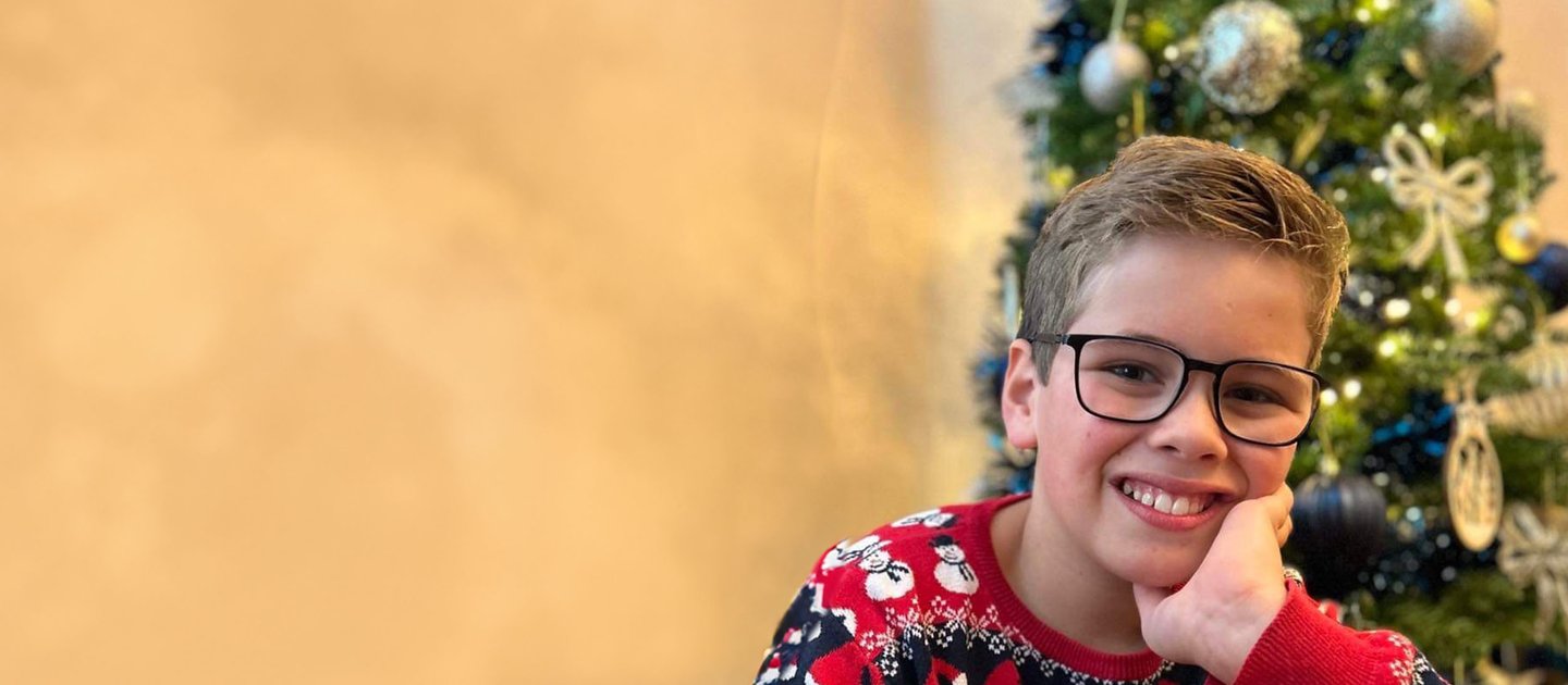Jacob in a super cool Christmas jumper in front of a Christmas tree