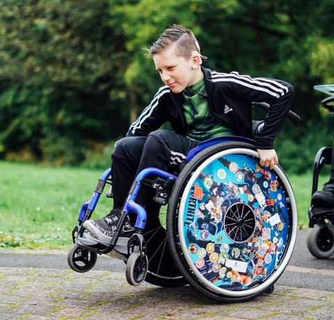 A you wheelchair user looks cool as he does a wheely in his blue wheelchair
