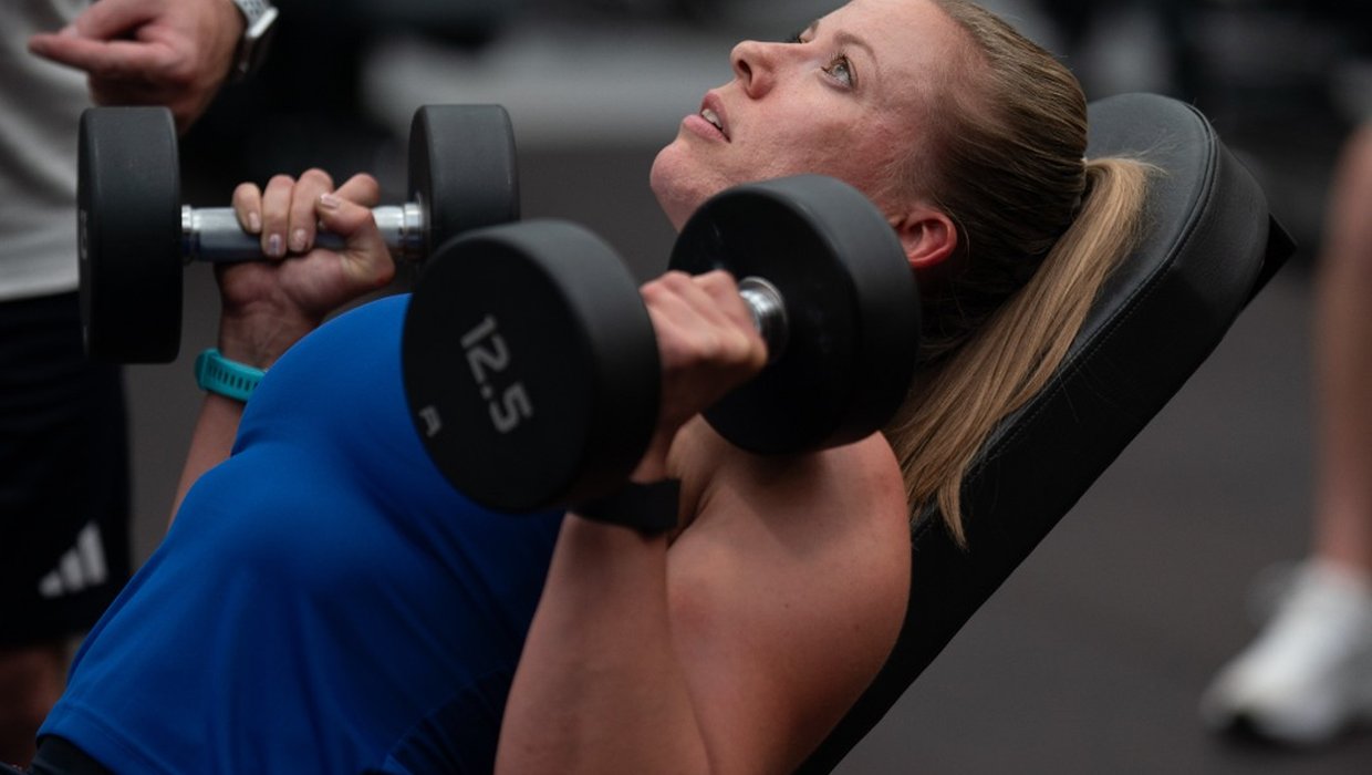 Hannah lifting weights in the pre-Paris training camp Hannah Cockcroft lifting weights. She is wearing a blue vest