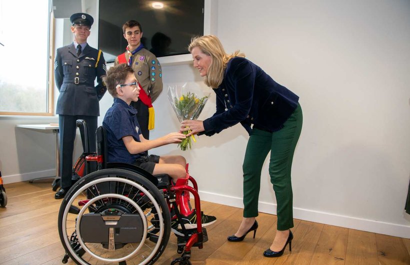 HRH presenting a young wheelchair user with a bunch of flowers