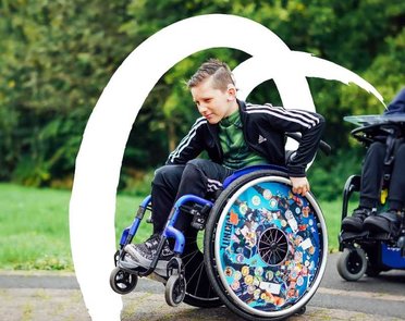 A young wheelchair user rolls on his back wheels