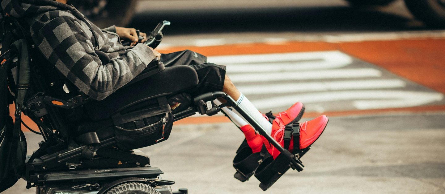 A person with bright red shoes sits reclined in a power chair