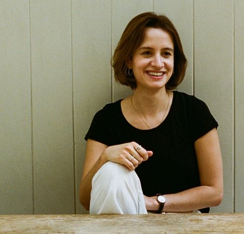 Celestine Fraser sat at a table. She has dark hair and is smiling at the camera.