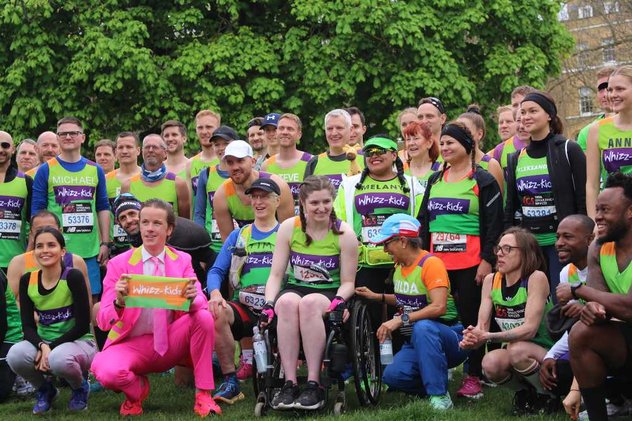 A large group of runners in the Whizz Kidz green vest posing for a group photo