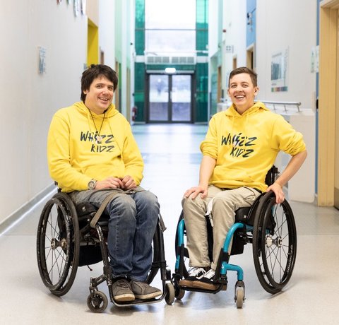 Rich and Nix our wheelchair skills trainers sitting next to each other in their yellow Whizz Kidz hoodies