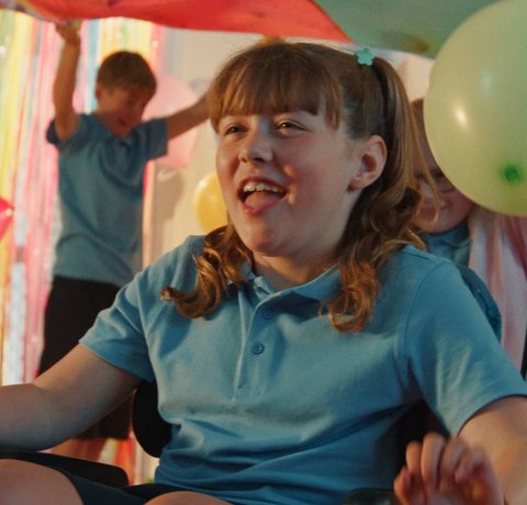 Ambers wheels under a brightly coloured banner with a green balloon in shot