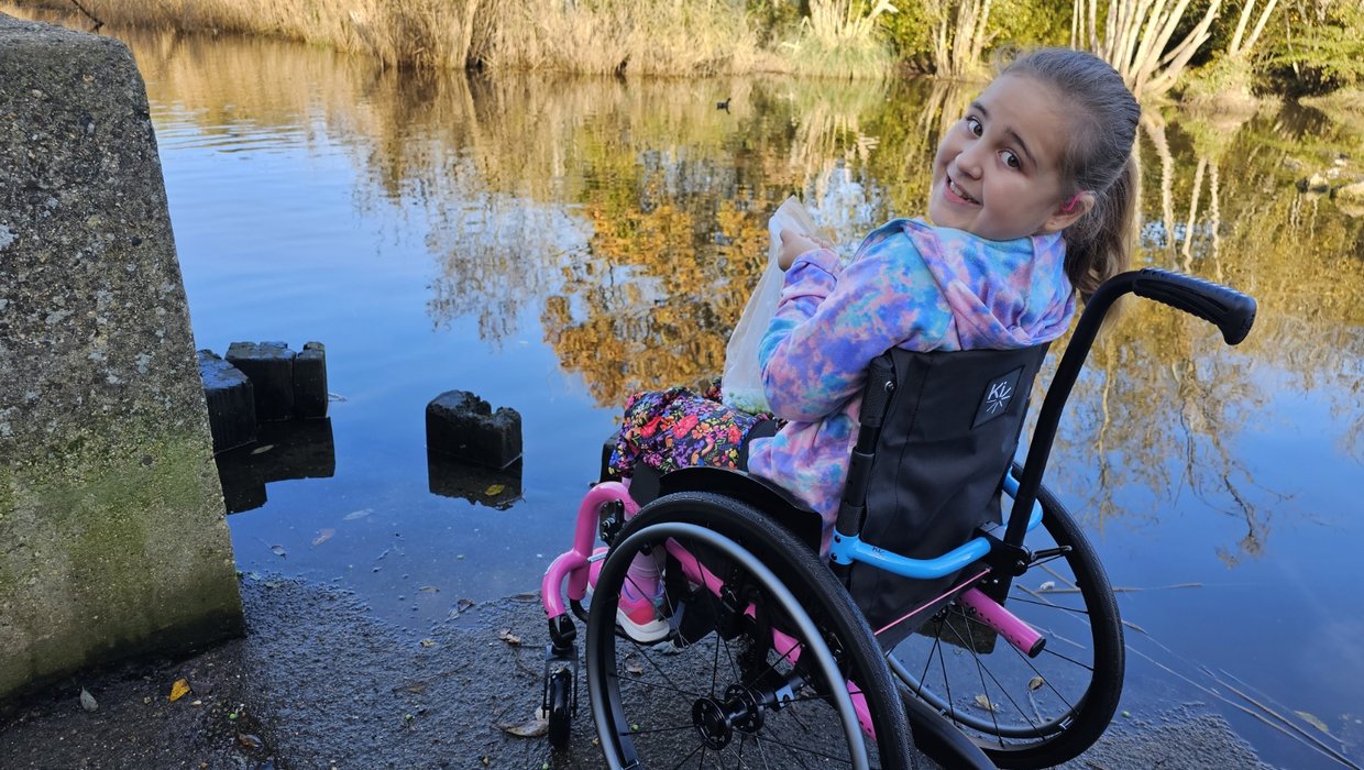 A young wheelchair user sits by a river